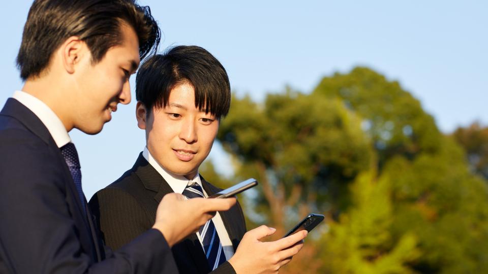 スマートフォンで連絡を取り合うビジネスマン。仕事の一時的なやり取りのイメージ